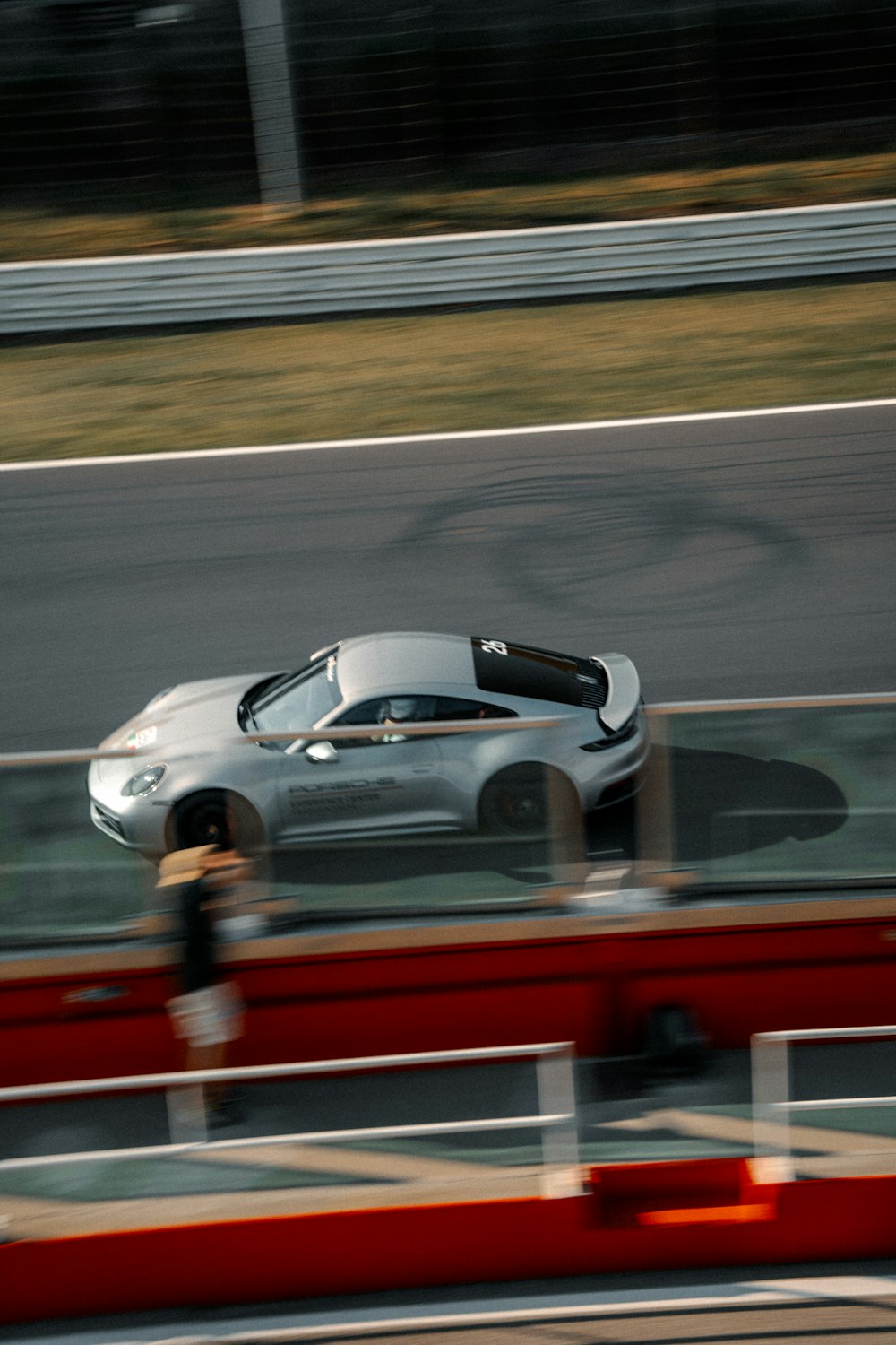 a silver sports car driving down a race track