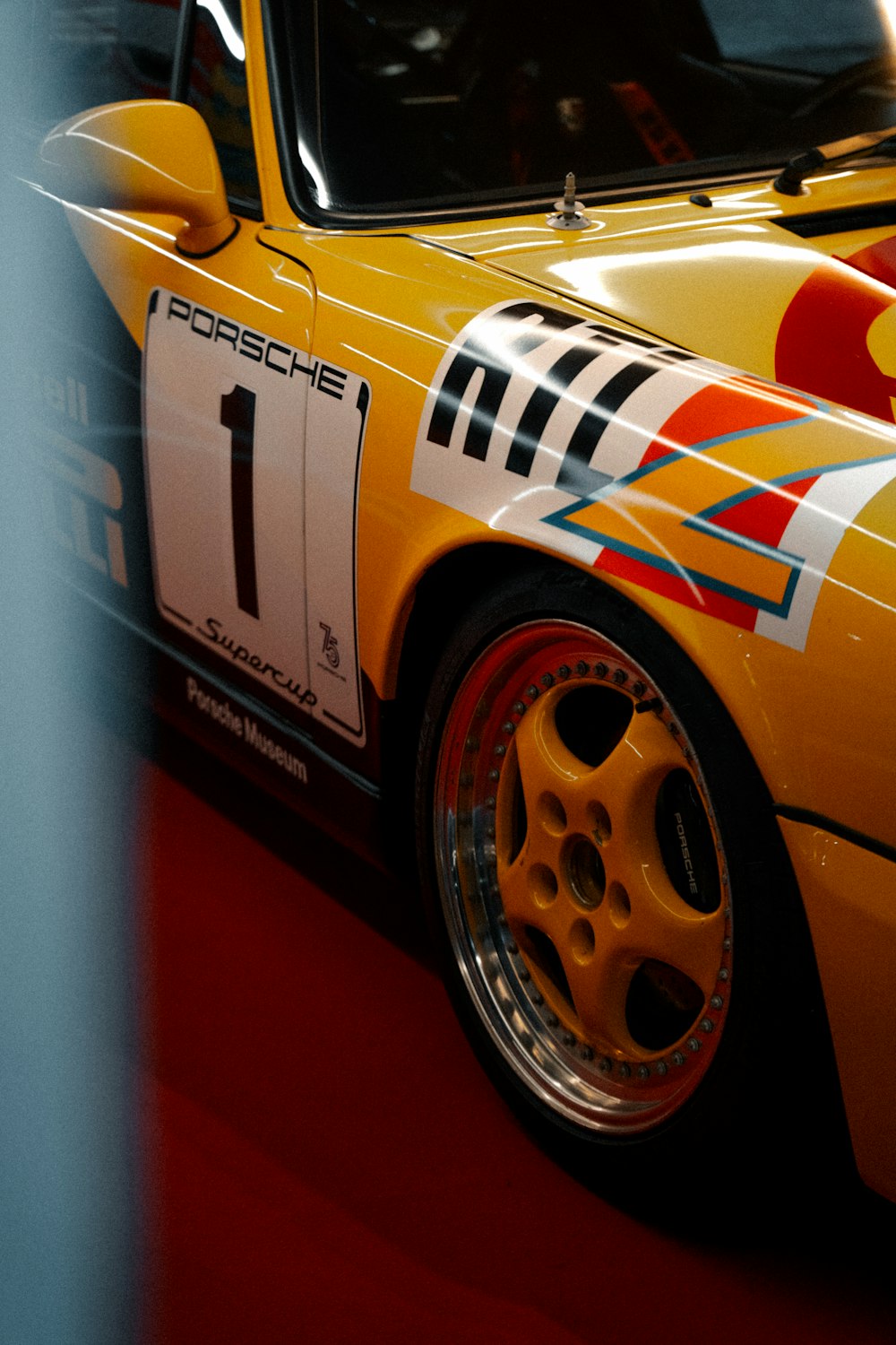 a yellow porsche sports car on display in a museum