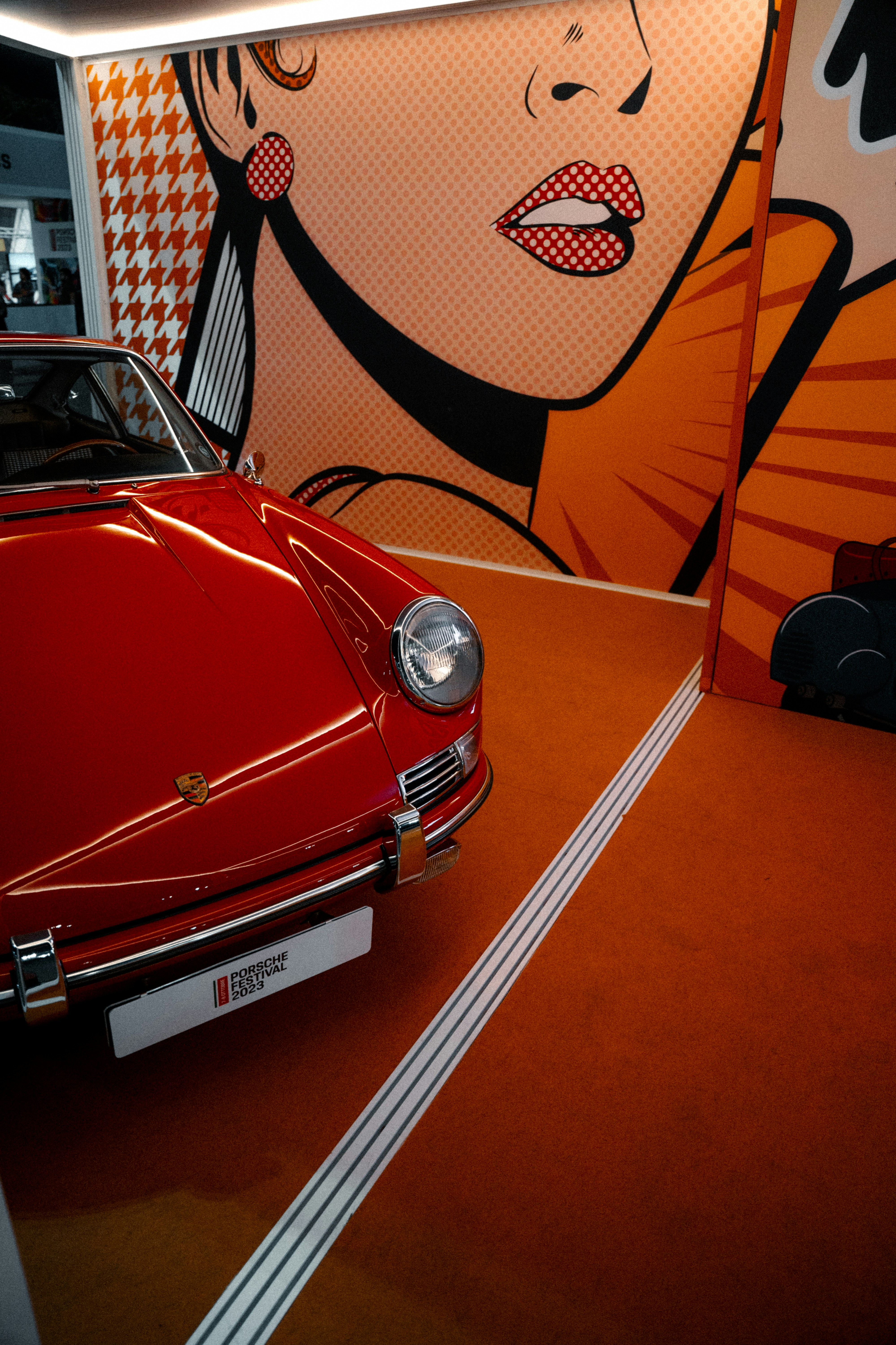 a red car parked in front of a painting