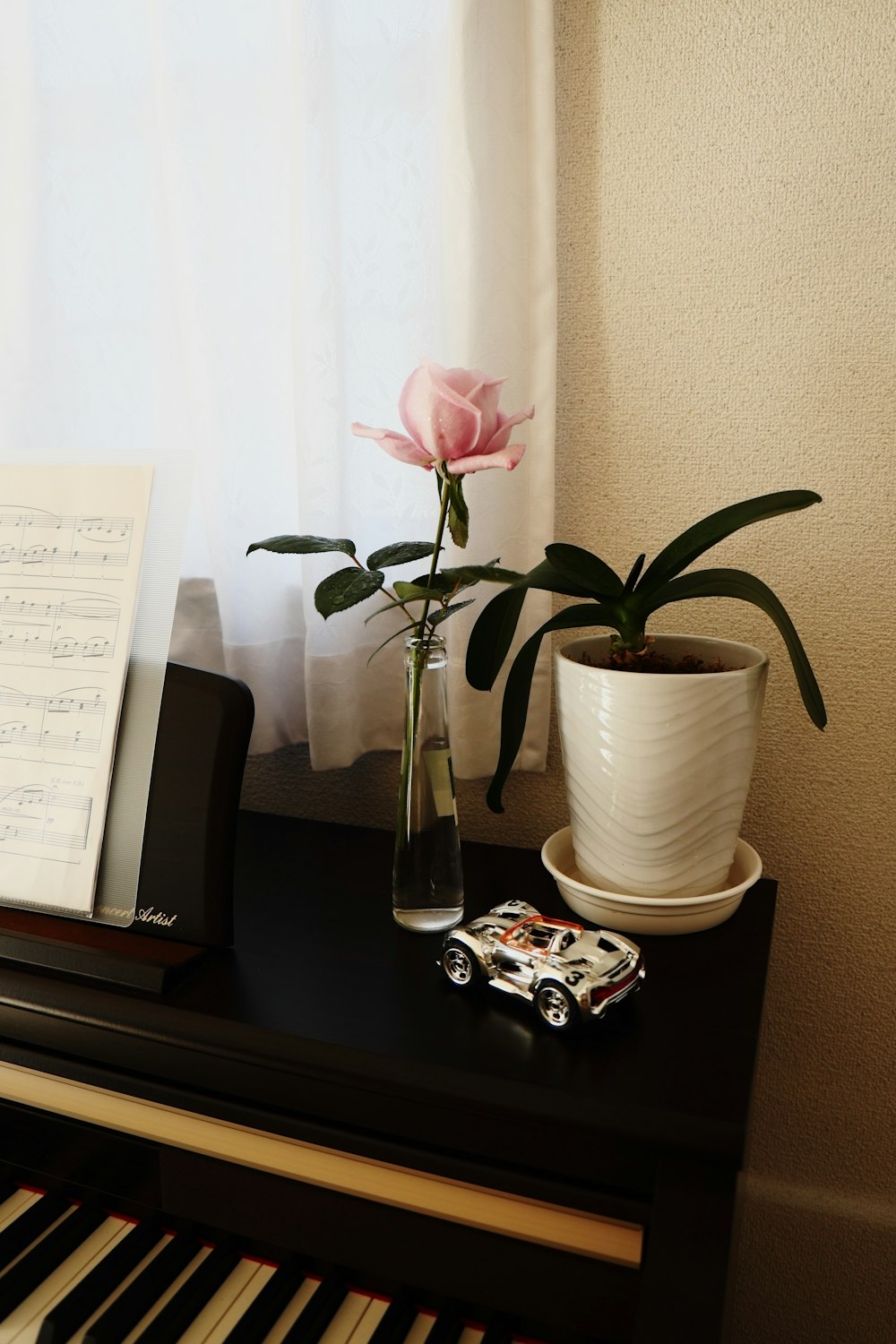a piano, a vase with a flower and a sheet of music