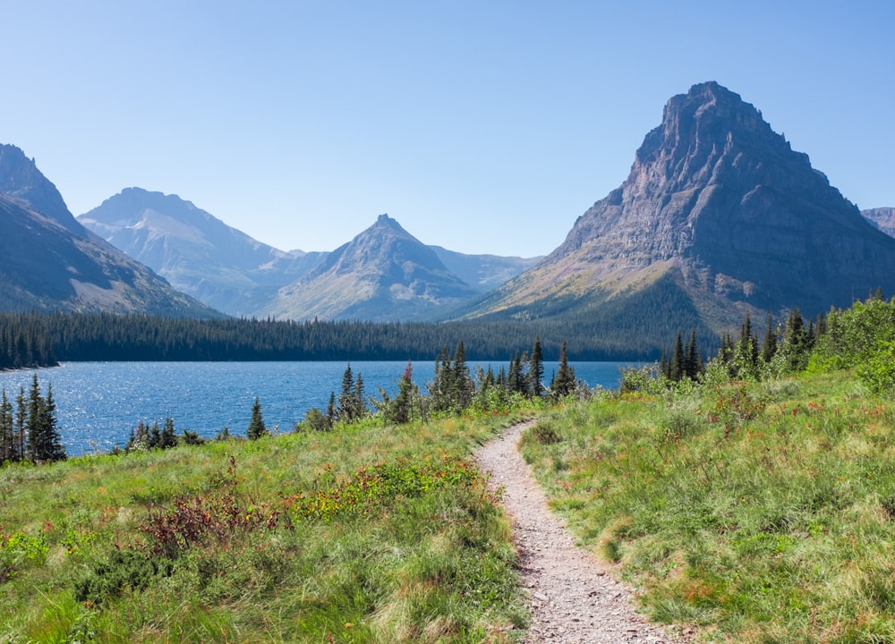 a trail leading to a lake with mountains in the background