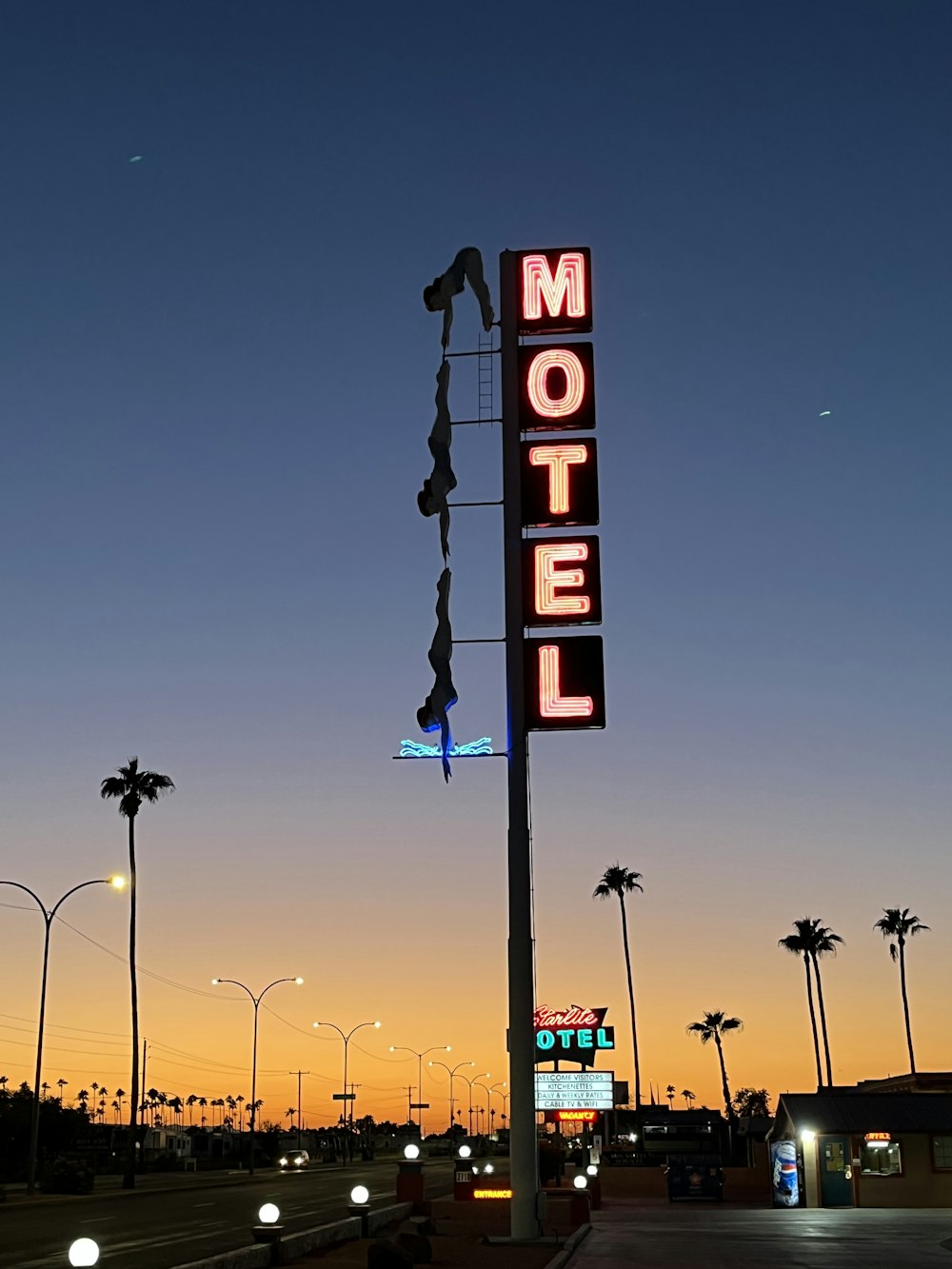 a motel sign at dusk with palm trees in the background