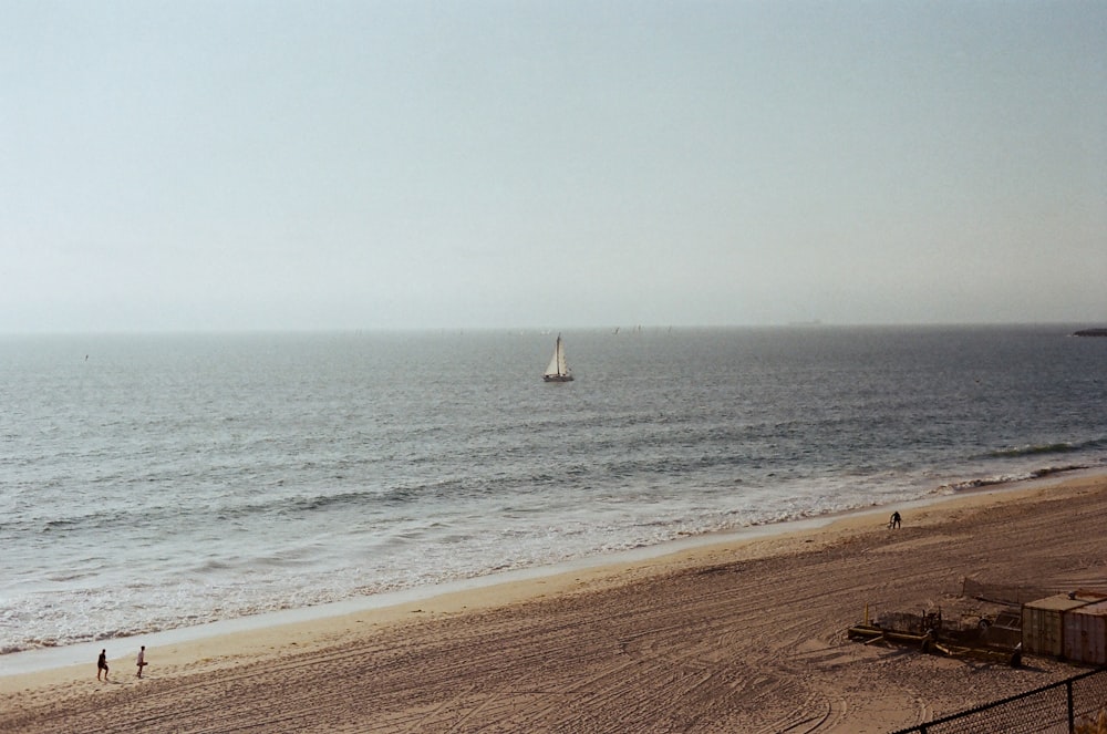 a beach with a sailboat in the distance