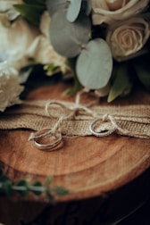 Close-up of wedding rings resting on a rustic wooden table with flowers.