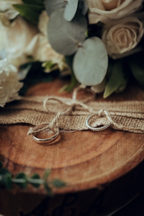 Close-up of delicate wedding rings resting on a rustic wooden surface.