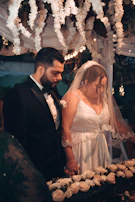 The couple exchanging vows under a simple arch decorated with light beige flowers.