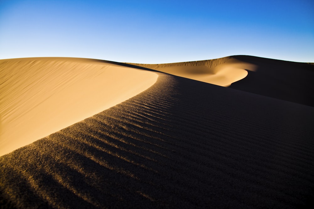 a large sand dune with a blue sky in the background