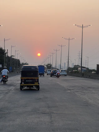 A fleet of Velostra trucks moving smoothly along a busy Indian highway at sunset.