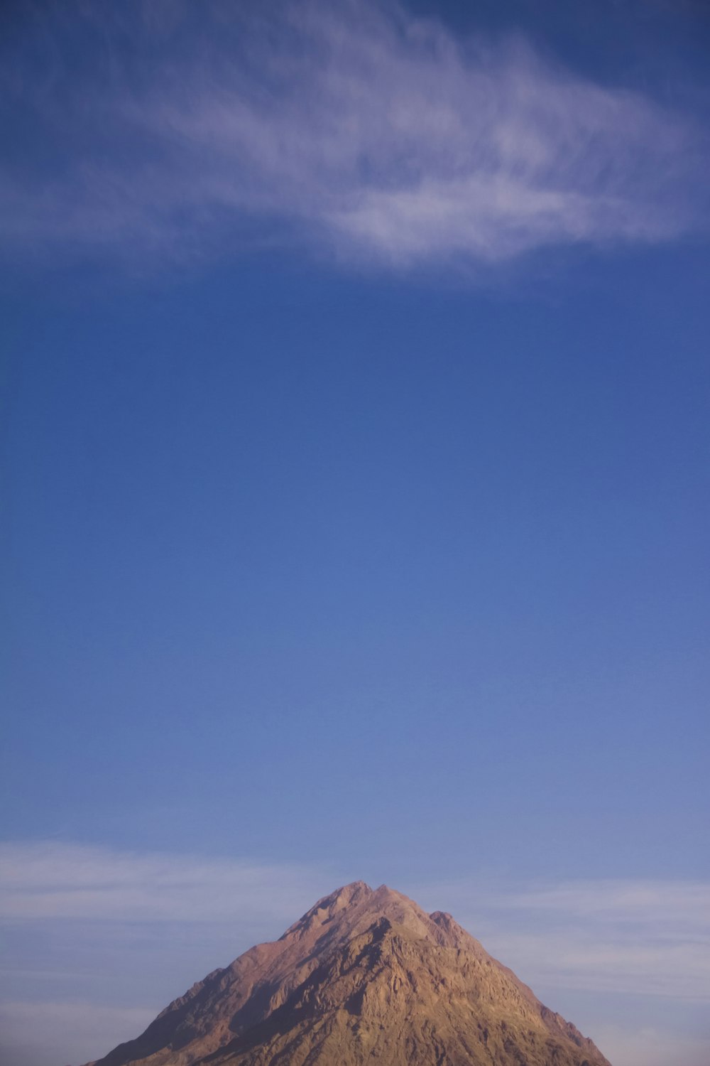 a large brown mountain with a blue sky in the background