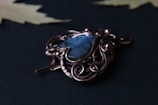 Close-up of a wire-wrapped pendant featuring antique pocket watch gears and a deep blue natural stone.