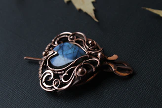 Close-up of a rugged pendant featuring deep blue lapis lazuli set in weathered silver, resting on a piece of driftwood.