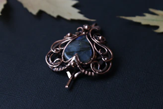 A beautifully designed gold pendant with a subtle blue gemstone centerpiece, reflecting the brand’s colors.