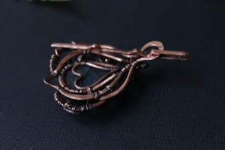 A handcrafted wire sculpture shaped into a heart, intricately twisted and placed on a dark background.