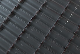 Rows of empty, transparent glass bottles are neatly aligned in a diagonal pattern. The bottles are clean and evenly spaced, creating a unified and geometric appearance. Soft reflections of light enhance the transparency of the glass.