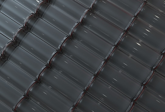 Rows of empty, transparent glass bottles are neatly aligned in a diagonal pattern. The bottles are clean and evenly spaced, creating a unified and geometric appearance. Soft reflections of light enhance the transparency of the glass.