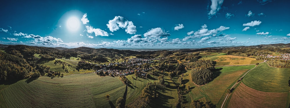 an aerial view of a green field with a village in the distance