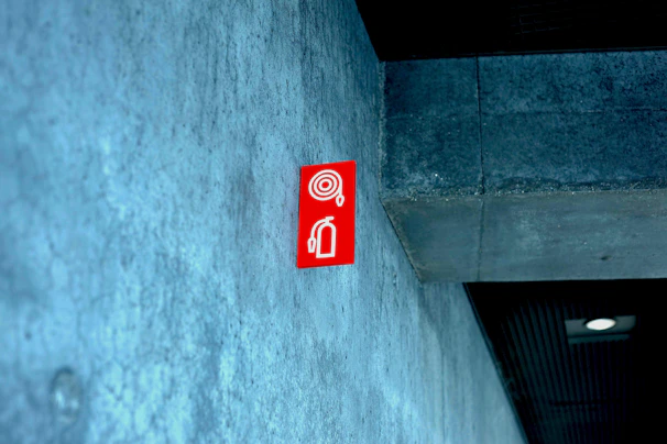Red fire extinguisher mounted on a gray wall with clear signage.