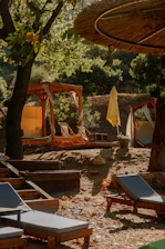 A cozy garden corner featuring a folding lounge chair with a sun canopy, surrounded by lush greenery.