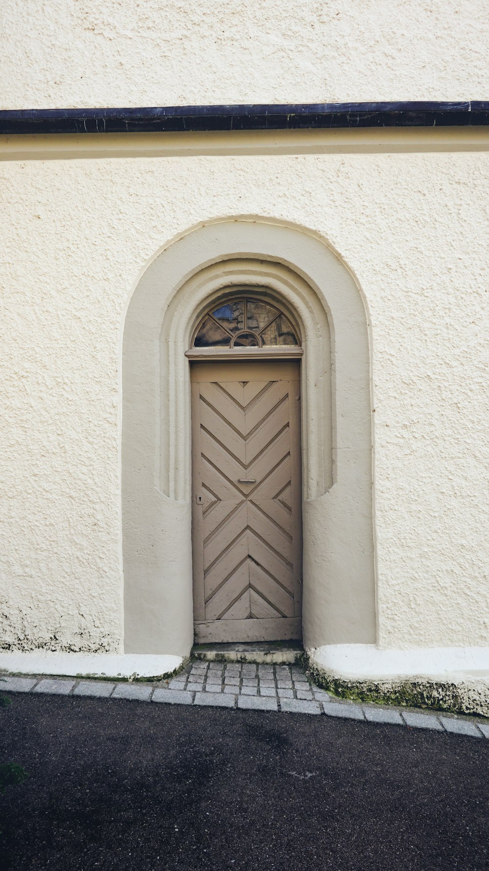 a white building with a brown door and a brick walkway