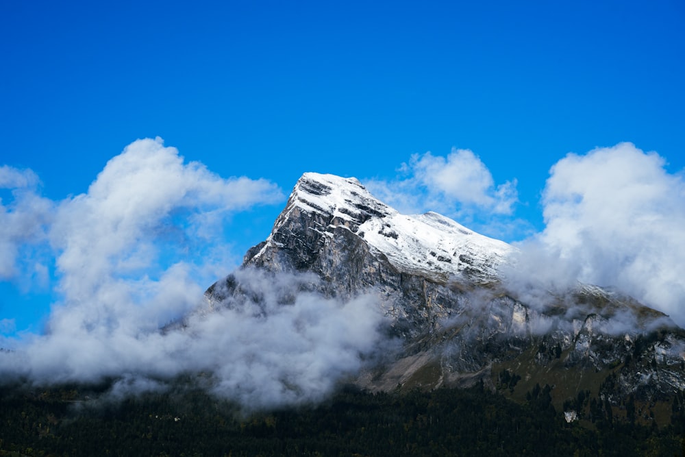 a mountain covered in clouds with a blue sky in the background