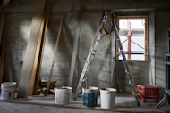 a ladder and buckets of paint in a room under construction