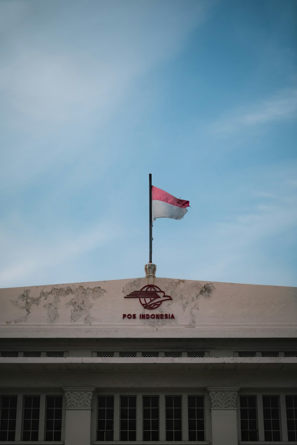 a flag on top of a building with a sky background