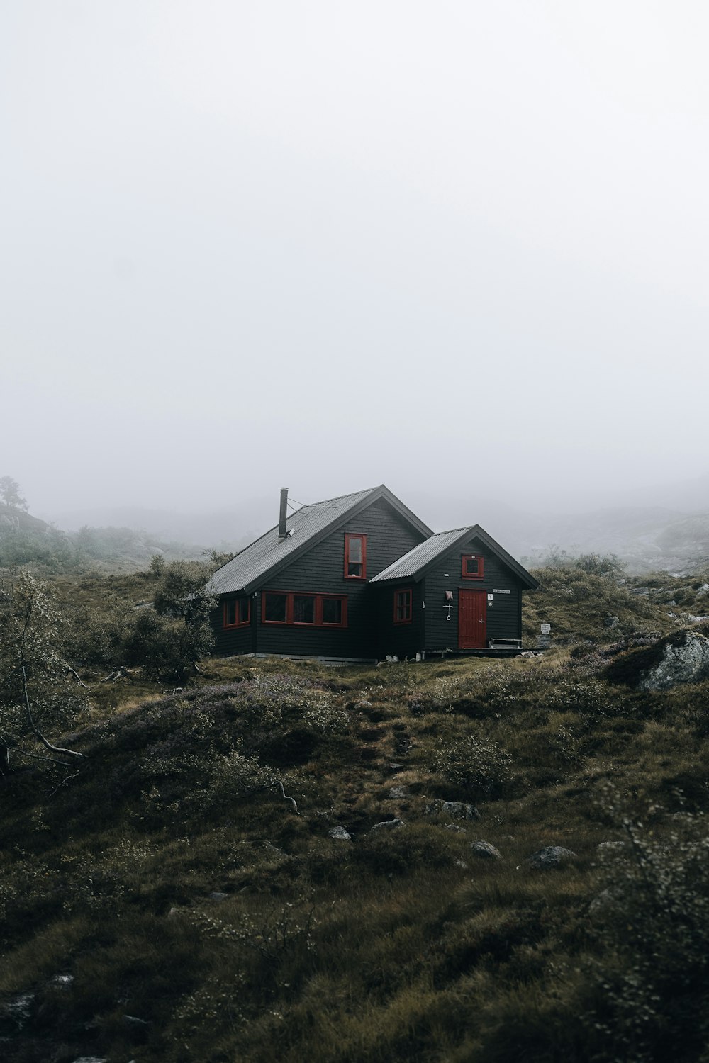 a black house in the middle of a foggy field