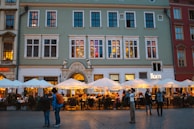 Families dining al fresco at a vibrant plaza with string lights overhead.