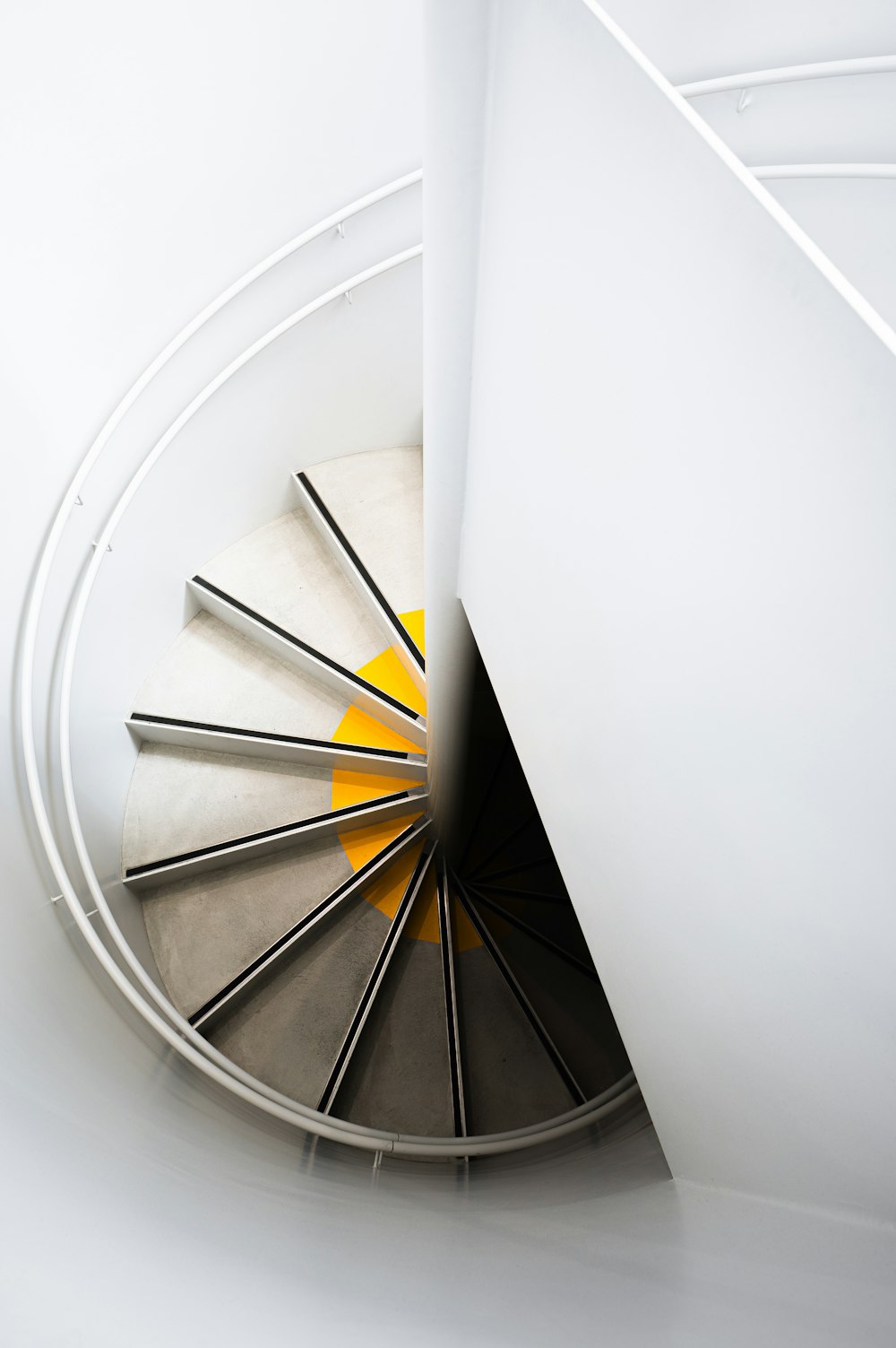 a spiral staircase in a white room with yellow accents