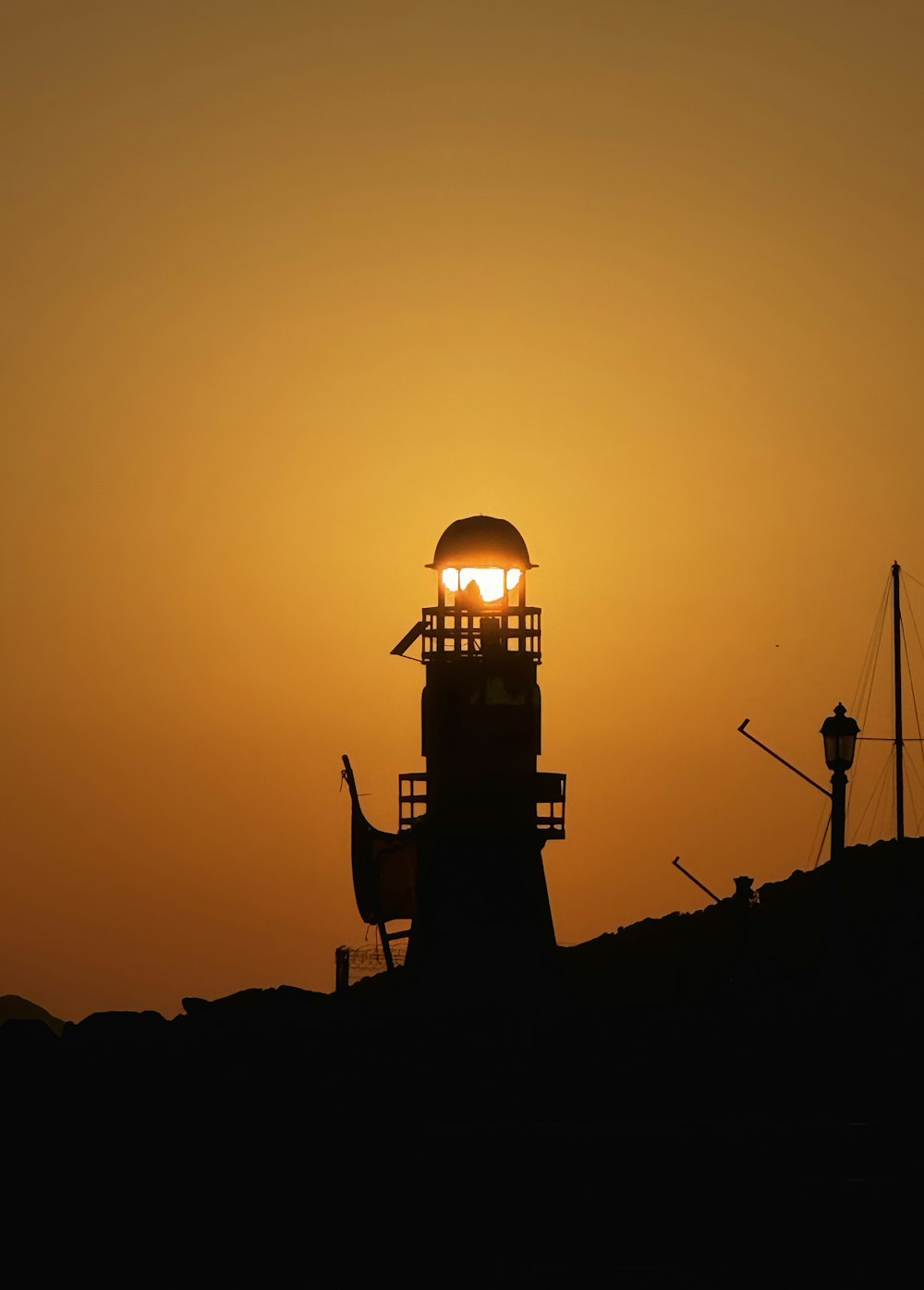 the sun is setting behind a light house