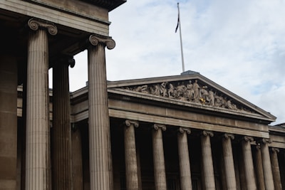 a tall building with columns and a flag on top of it