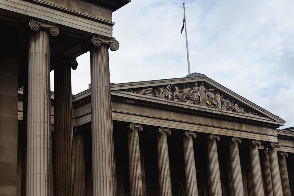 a tall building with columns and a flag on top of it