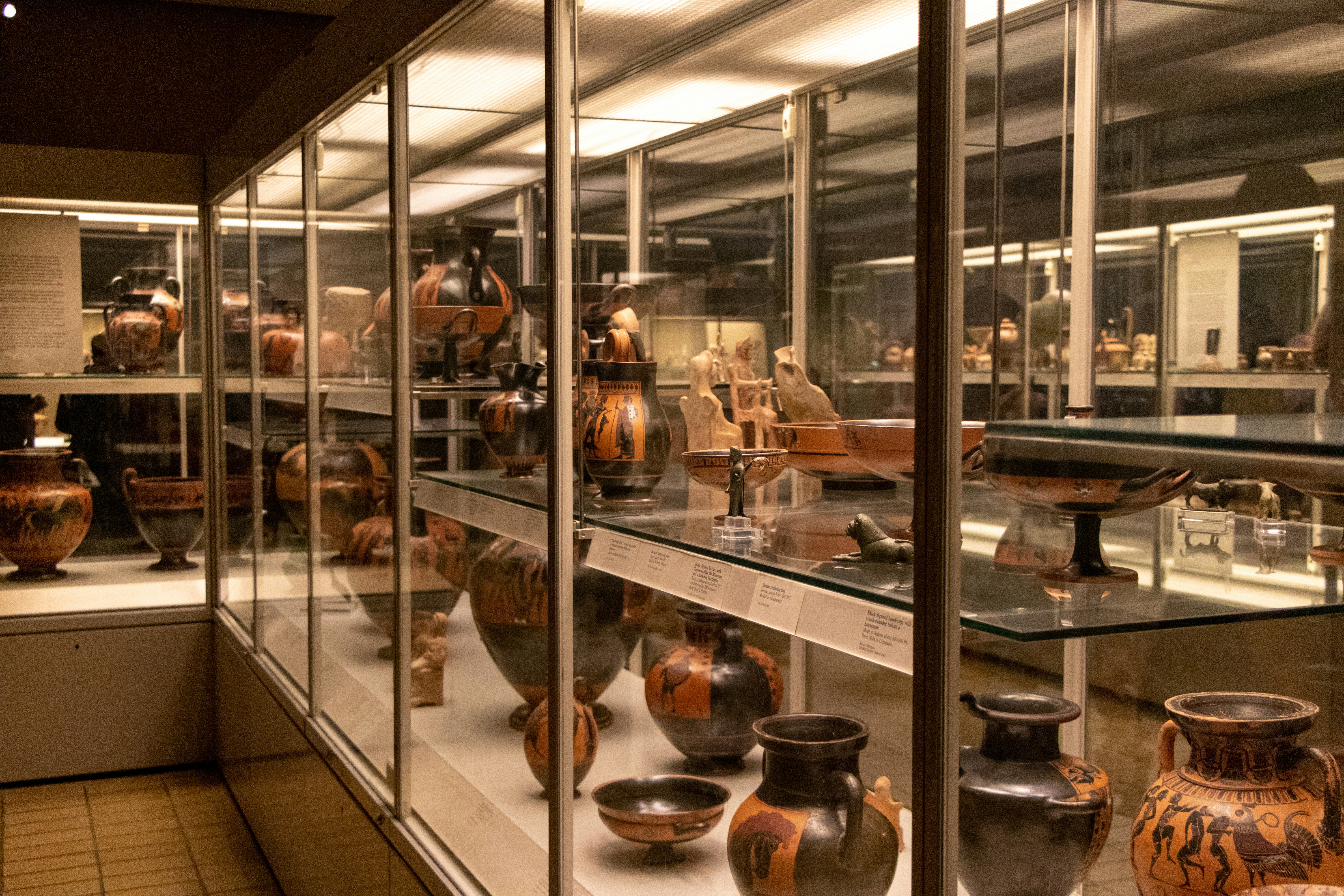 Ancient terracotta pottery with geometric patterns, warm earth tones, museum display on dark surface