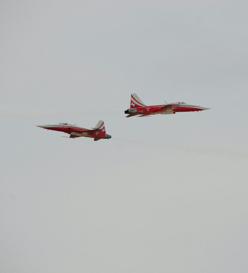 two red and white jets flying in the sky