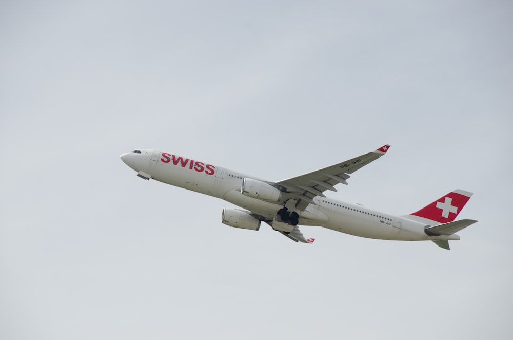 a swiss airplane is flying in the sky
