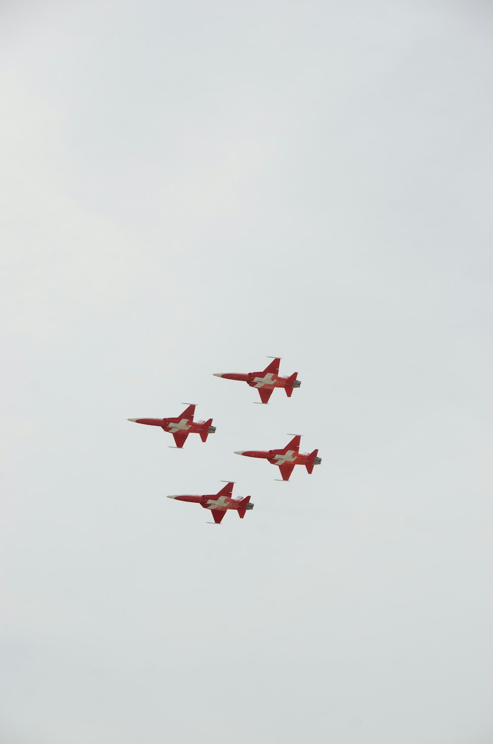 a group of red fighter jets flying through a cloudy sky