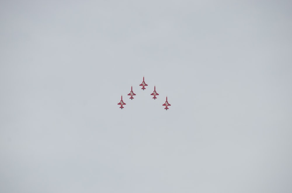 a group of fighter jets flying through a cloudy sky