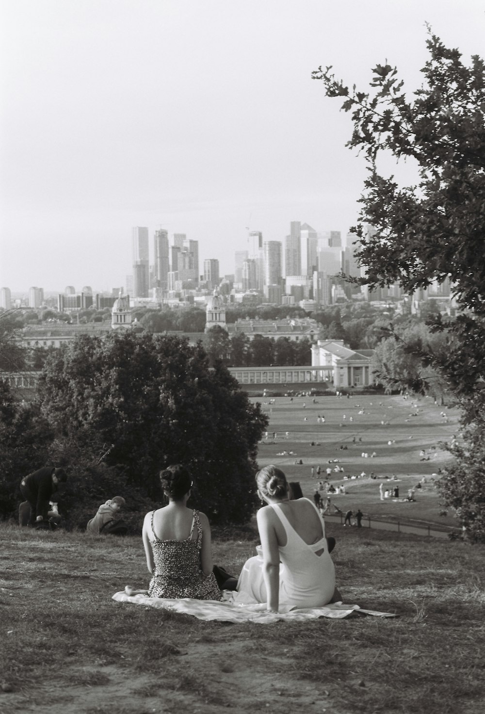 a couple of women sitting on top of a grass covered field
