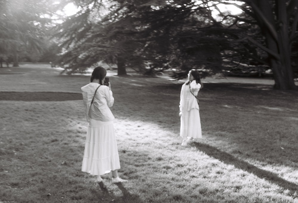 a black and white photo of two women in a park