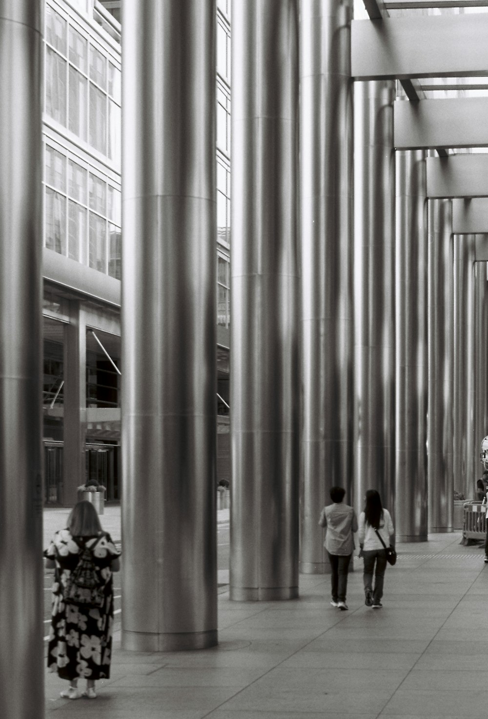 a black and white photo of people walking down a walkway