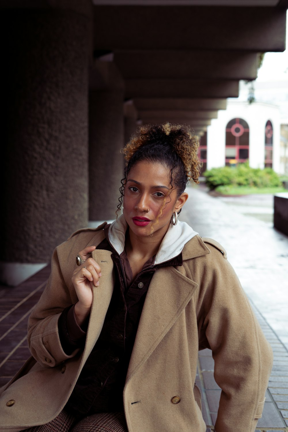 a woman sitting on a bench with a coat over her shoulder