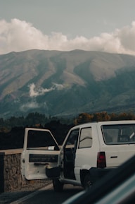 Professional driver opening the door of a high-end vehicle in front of a mountain resort.