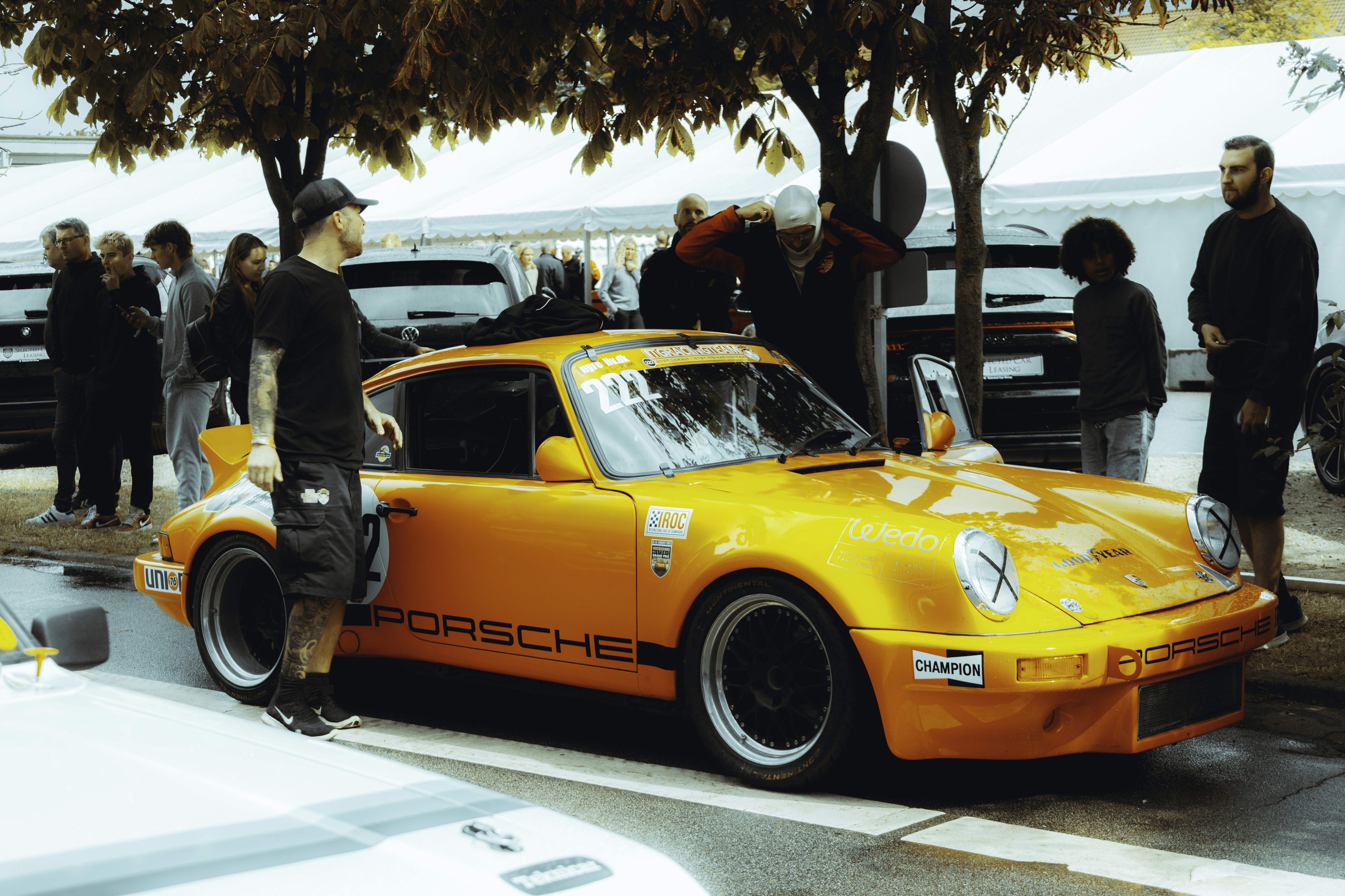 a group of people standing around a yellow car