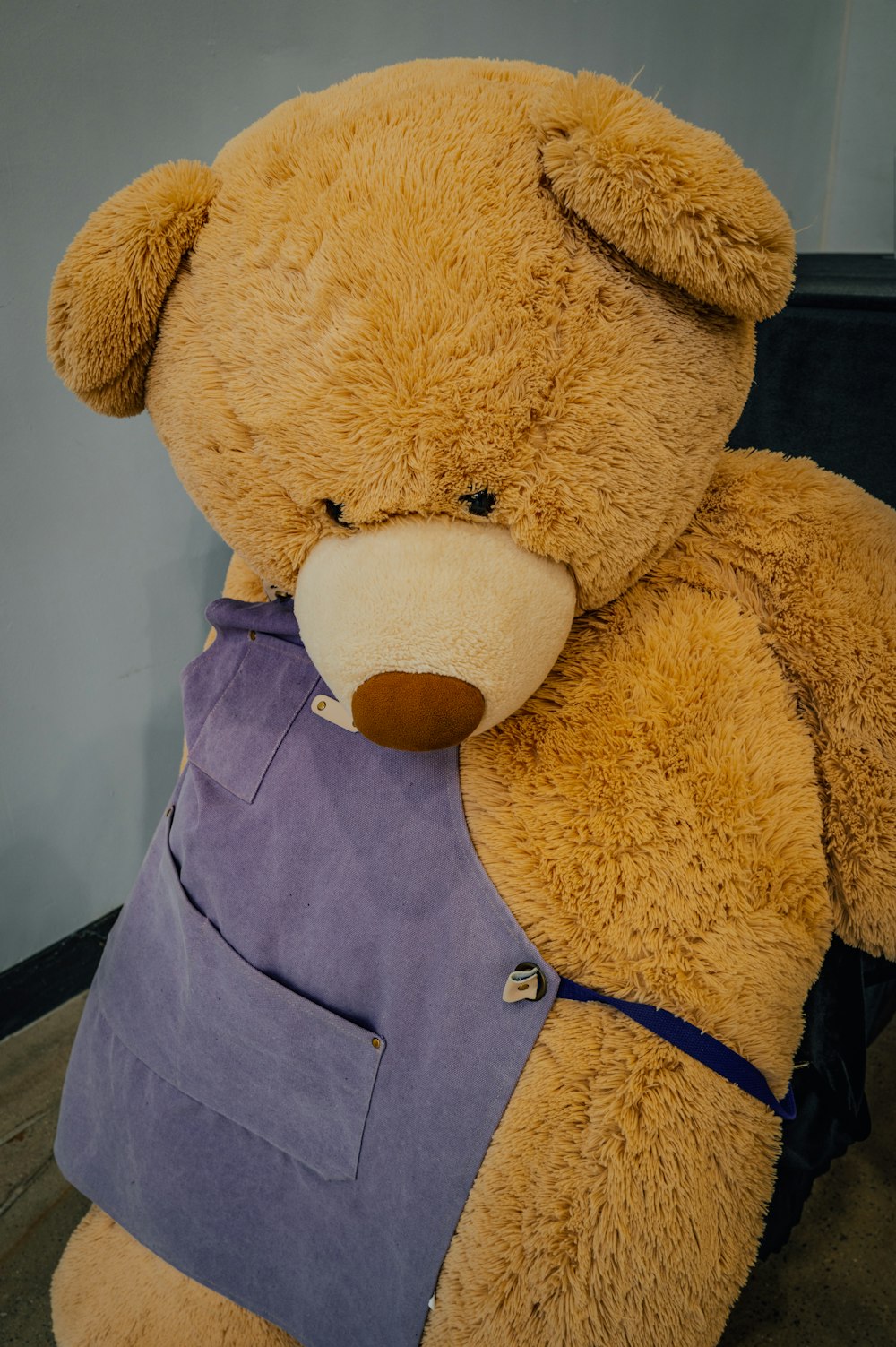 a large brown teddy bear sitting on top of a wooden floor