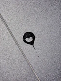 A blood-red stain spreading across a cracked concrete floor, symbolizing hidden violence.