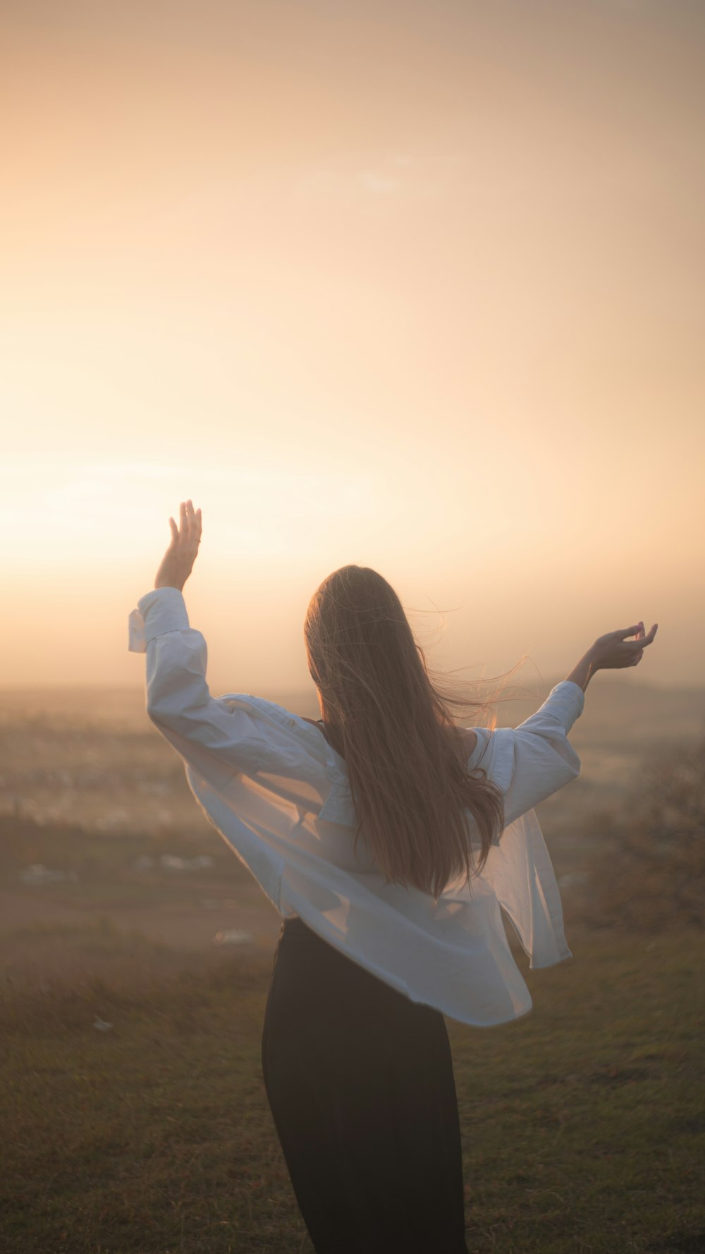 a woman standing in a field with her arms outstretched