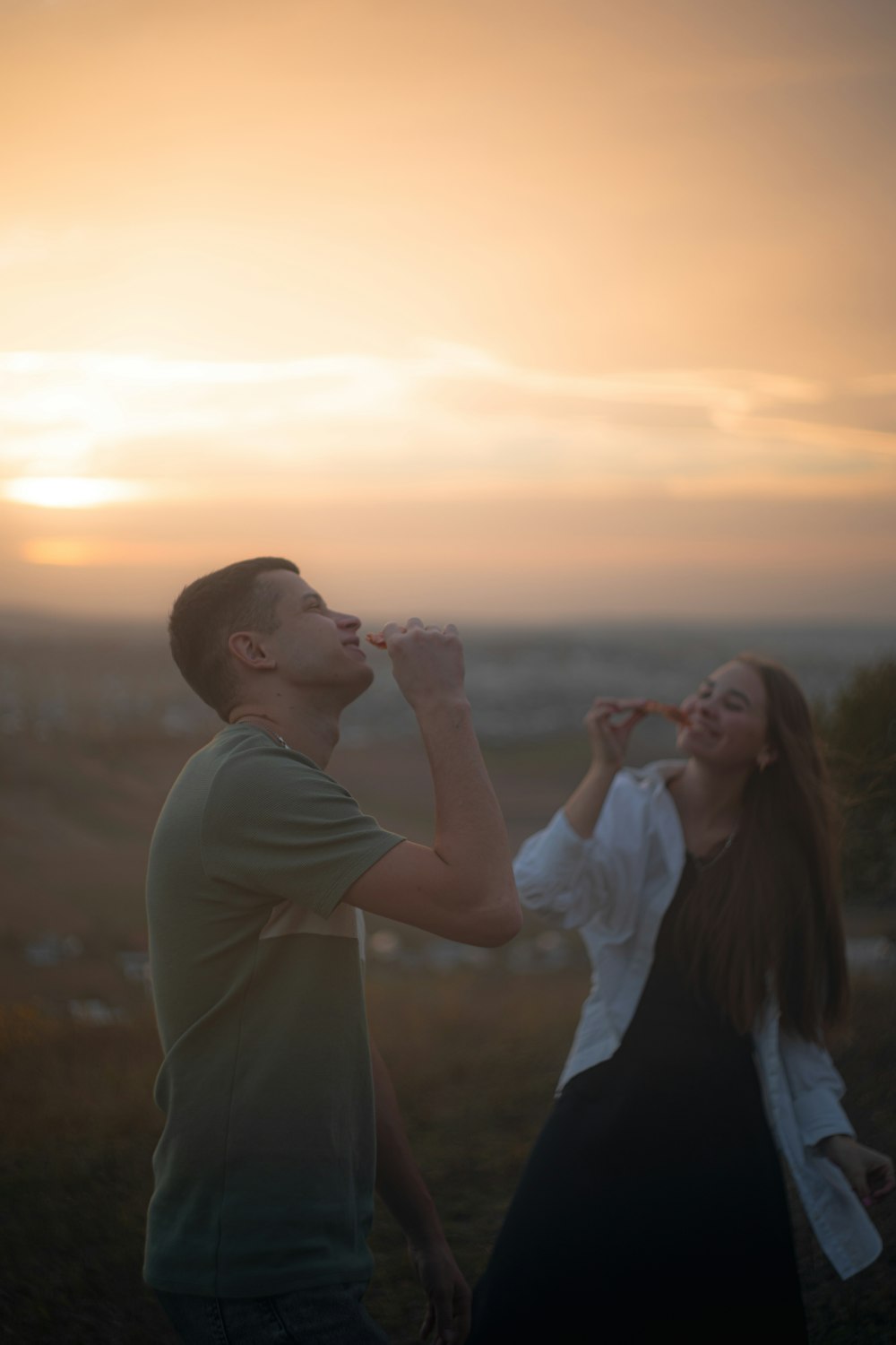 a man and a woman standing in a field drinking water