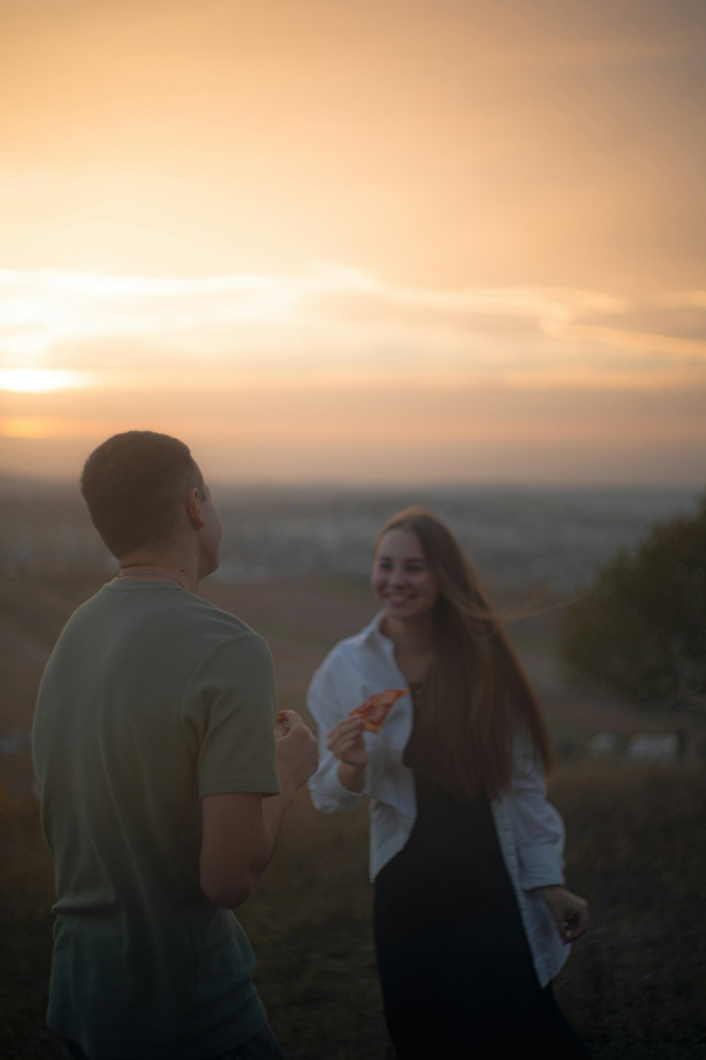 a man and a woman standing in a field at sunset