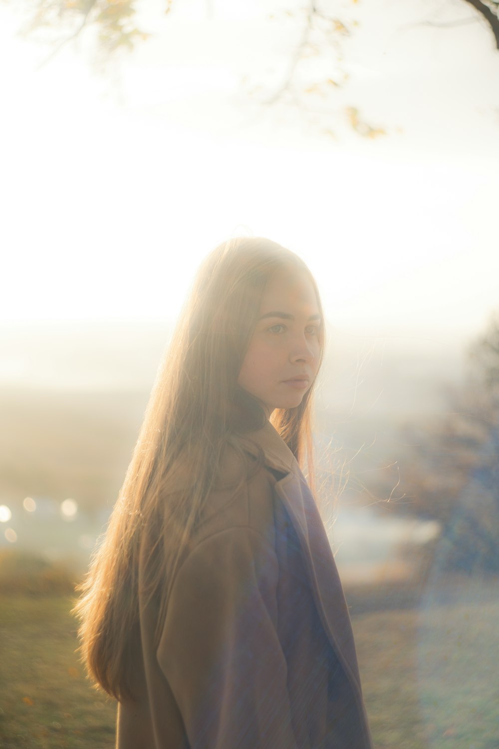 a woman standing in a field next to a tree