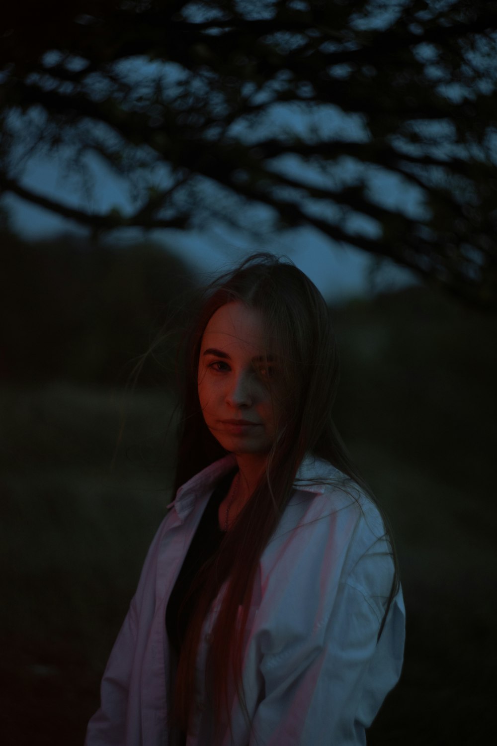 a woman standing under a tree at night